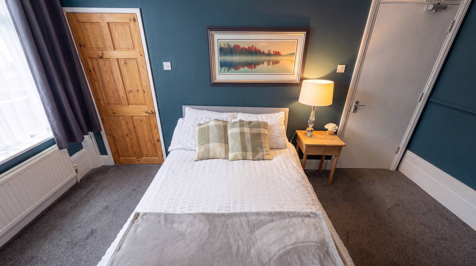 A calm guest room with white linen and a framed landscape